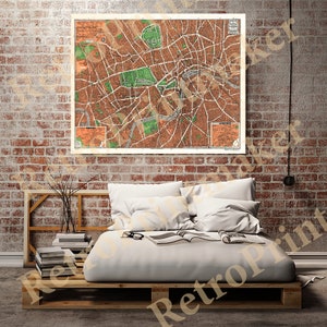 May include: A vintage map of London, England, printed on paper with a brown and green color scheme. The map is framed and hanging on a brick wall above a bed with white bedding.