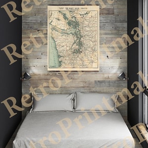 May include: A vintage map of the Puget Sound Country, Washington State, printed on paper with a cream background. The map is framed and hanging on a wood wall above a bed with white bedding.