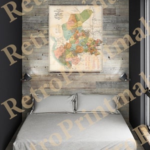 May include: A vintage map of Buffalo and its surrounding area, printed in muted colors and featuring detailed lines and text. The map is framed and hanging on a wood-paneled wall above a bed with white linens.