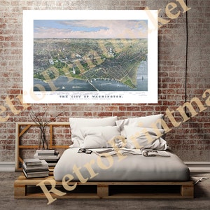 Puede incluir: Una impresión enmarcada de un mapa antiguo de Washington, D.C., con una vista aérea detallada de la ciudad, incluido el río Potomac. La impresión se muestra en una pared de ladrillo sobre una cama hecha de palets de madera.