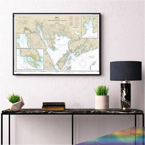 May include: A framed nautical chart of Passamaquoddy Bay and St. Croix River, Maine, USA. The chart shows the coastline, islands, and waterways of the region. The chart is printed on cream-coloured paper with black text and lines.