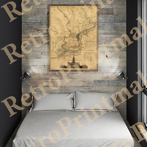 May include: A vintage map of Philadelphia, Pennsylvania, printed on aged paper, hangs on a wood-paneled wall above a bed with white linens. The map shows the city's streets, waterways, and surrounding areas.