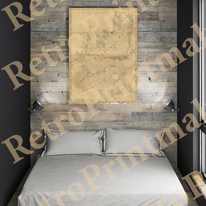 May include: A vintage map of the coast of Norway, framed and hanging on a wall above a bed with white linen sheets in a rustic bedroom with wood panelling.