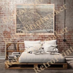 May include: An antique map of Austin, Texas, framed and displayed on a brick wall. The map is in shades of beige and brown, showing the city's layout. The word "Austin" is visible at the bottom. The map is above a bed made of pallets.
