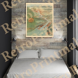 May include: A vintage illustration of a city with a river running through it. The illustration is printed on paper and framed in a wooden frame. The frame is hanging on a wood-paneled wall above a bed with white linens.