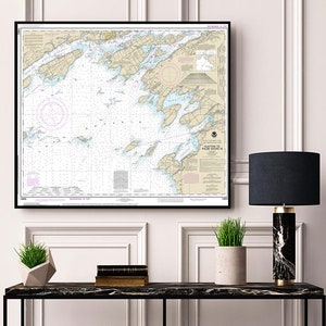 Könnte beinhalten: Eine gerahmte Seekarte der Küste von Maine mit detaillierten Markierungen und Text. Die Karte hängt an einer weißen Wand über einem schwarzen Konsolentisch mit einer Lampe, einer Topfpflanze und Büchern.