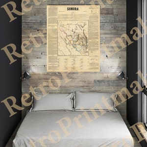 Könnte beinhalten: Eine Vintage-Karte von Sonora, Mexiko, gedruckt auf Papier mit braunem Rand. Die Karte ist gerahmt und hängt an einer Holzwand über einem weißen Bett mit zwei Kissen.