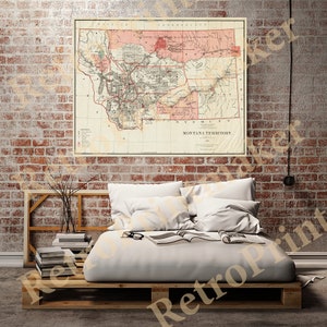 Pode incluir: Um mapa antigo do Território de Montana, impresso em preto e branco com acentos vermelhos. O mapa mostra os condados do território e as principais cidades, incluindo Helena, Virginia City e Deer Lodge. O mapa está emoldurado e pendurado em uma parede de tijolos.