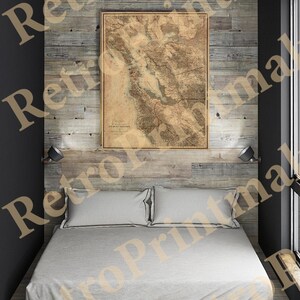Könnte beinhalten: Eine antike Karte der San Francisco Bay Area, gedruckt auf gealtertem Papier, hängt an einer mit Holz verkleideten Wand über einem Bett mit weißen Bettwäsche. Die Karte zeigt die Bucht von San Francisco mit ihren umliegenden Bergen und Flüssen.