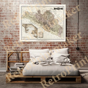 May include: A vintage map of the state of Guerrero, Mexico, printed on cream-colored paper with brown and green details. The map is framed and hanging on a brick wall above a white bed with white pillows and a book on top.