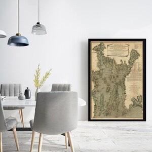 May include: A vintage map of Port Jackson, New South Wales, Australia, printed in 1788. The map shows the coastline, inlets, and surrounding land features. The map is framed in black and displayed on a white wall.