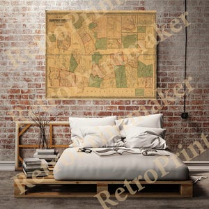 Puede incluir: Un mapa vintage del condado de Hampden, Massachusetts, impreso en papel y enmarcado en un marco de madera. El mapa está colgado en una pared de ladrillo sobre una cama con ropa de cama y almohadas blancas.