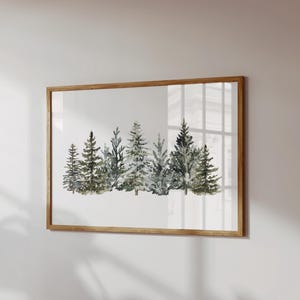 Può includere: Una stampa artistica da parete rettangolare che presenta un'illustrazione ad acquerello di una fitta foresta di alberi sempreverdi in tonalità verde scuro e grigio tenue, racchiusa in una cornice di legno chiaro, sottile e semplice.