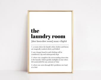 May include: A framed print with the words "the laundry room" in a bold, black font. The definition of "laundry room" is provided below the title, along with four humorous descriptions of the laundry process.