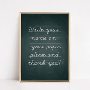 May include: A framed chalkboard with a gold border. The chalkboard has a dark green background with white cursive text that reads "Write your name on your paper please and thank you!"