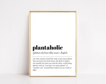 Puede incluir: Impresión enmarcada con la palabra "plantaholic" en negro. La definición describe a alguien que ama las plantas. El marco es dorado y el fondo es blanco.