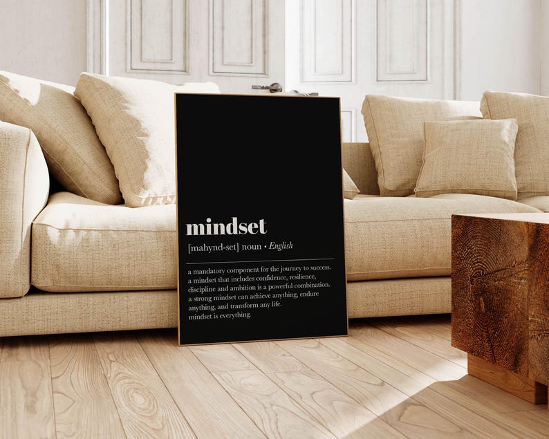 K&ouml;nnte beinhalten: Ein schwarzer gerahmter Druck mit dem Wort "mindset" in wei&szlig;em Text. Der Druck enth&auml;lt eine Definition des Wortes mit dem Text "a mandatory component for the journey to success..." Der Druck wird in einem Wohnzimmer gezeigt.
