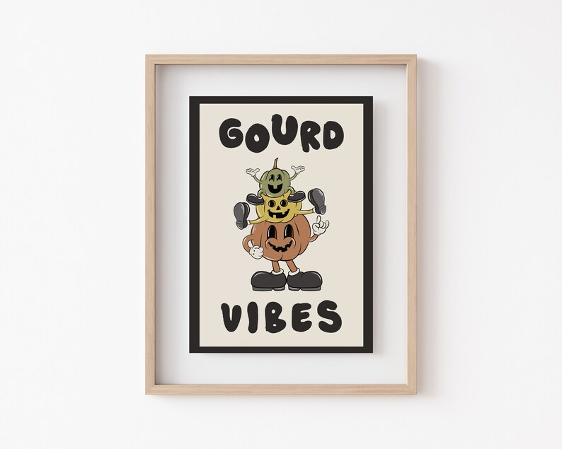 K&ouml;nnte beinhalten: Ein gerahmter Druck mit dem Text "GOURD VIBES" in schwarzen Buchstaben. Der Druck zeigt eine Cartoon-Illustration von drei &uuml;bereinander gestapelten K&uuml;rbissen mit l&auml;chelnden Gesichtern.