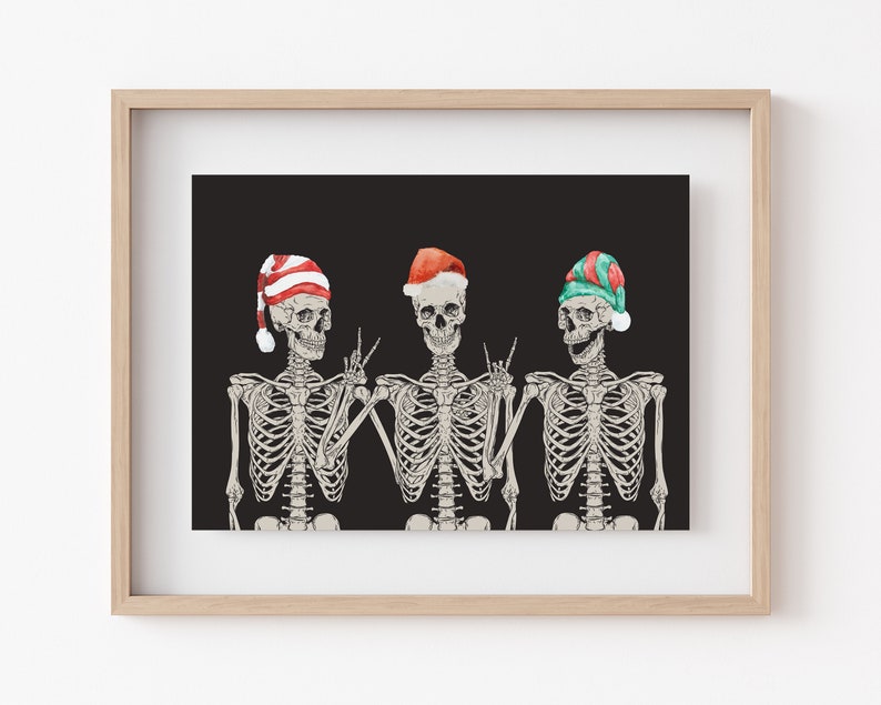 May include: A framed art print featuring three skeletons against a black background. Each skeleton wears a different Christmas-themed hat: one with red and white stripes, one solid red, and one with green and red stripes. The skeletons are gesturing.