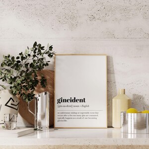 Peut inclure: Une affiche encadr&eacute;e avec le mot "gincident" et sa d&eacute;finition. L'affiche est sur une surface blanche avec un pichet en acier inoxydable, un verre et un vase d&eacute;coratif. Des branches vertes et feuillues sont &agrave; gauche.