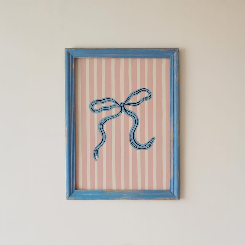 Pode incluir: Uma impress&atilde;o de arte retangular numa moldura de madeira azul-clara com aspeto envelhecido. A obra apresenta uma ilustra&ccedil;&atilde;o de linhas azul-escuras centrada de um la&ccedil;o de fita sobre um fundo de riscas verticais rosa-claro e branco.