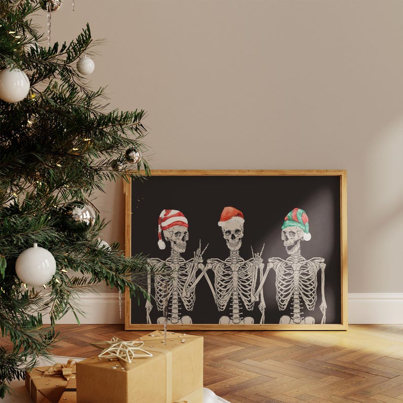 May include: A framed horizontal print on a black background featuring three white skeletons wearing festive hats. The left skeleton wears a red and white striped hat, the centre wears a red Santa hat, and the right wears a green and red striped hat.