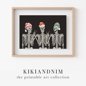 May include: A framed print featuring three skeletons against a black background. The skeletons wear festive hats in red, white, and green, with hand gestures including peace signs and rock-and-roll signals. The text KIKIANDNIM the printable art collection appears below.