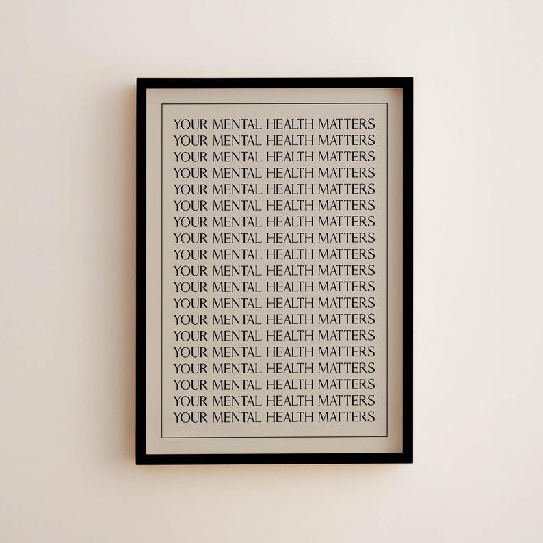May include: A framed print with the repeated text "YOUR MENTAL HEALTH MATTERS" in a black frame. The text is in a simple, sans-serif font, and the background is a light beige colour. The print is displayed on a light beige wall.