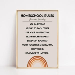 May include: A framed print with the text "HOMESCHOOL RULES for our family." The rules include "ASK QUESTIONS," "BE KIND TO EACH OTHER," and "REMEMBER TO HAVE FUN." A rainbow design is at the bottom of the print. The frame is gold.