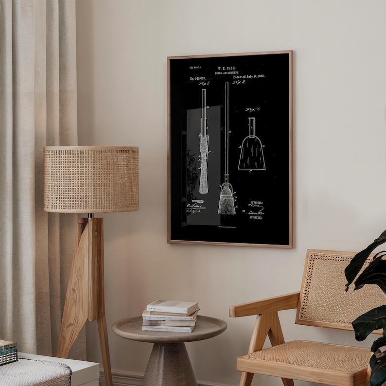 May include: A framed black and white print of a broom patent. The print shows detailed diagrams of a broom and its components, with text including the patent date of July 6, 1886. The print is displayed in a room with a wooden floor lamp and a woven chair.