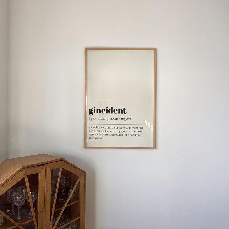 Peut inclure: Une affiche encadr&eacute;e avec le mot "gincident" en gras, en noir. La d&eacute;finition d&eacute;crit un &eacute;v&eacute;nement malheureux apr&egrave;s avoir consomm&eacute; trop de gin. Le cadre est de couleur marron clair.