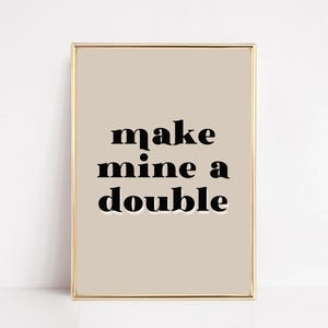 Op de afbeelding: Een witte keramische mok met een zwarte handgreep en de tekst "But First, Coffee" in een vetgedrukte, zwarte letter. De mok staat tegen een vage achtergrond, wat een gezellige setting suggereert.