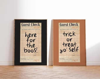 May include: Two framed prints with a vintage receipt design. One print says "here for the boos!" in black text on a tan background, framed in black. The other says "trick or treat yo' self" in black text, framed in brown.