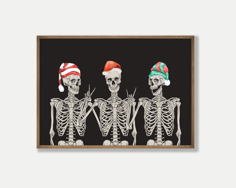 May include: A framed wall art print featuring three skeletons against a solid black background. Each skeleton wears a different holiday hat: one with red and white stripes, one solid red, and one with green and red stripes, all with white pom-poms.