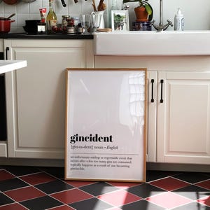 Peut inclure: Un cadre avec le mot "gincident" dans une cuisine. La d&eacute;finition de "gincident" est en dessous du mot. La cuisine a des armoires blanches, un &eacute;vier et un sol &agrave; carreaux rouges et noirs.