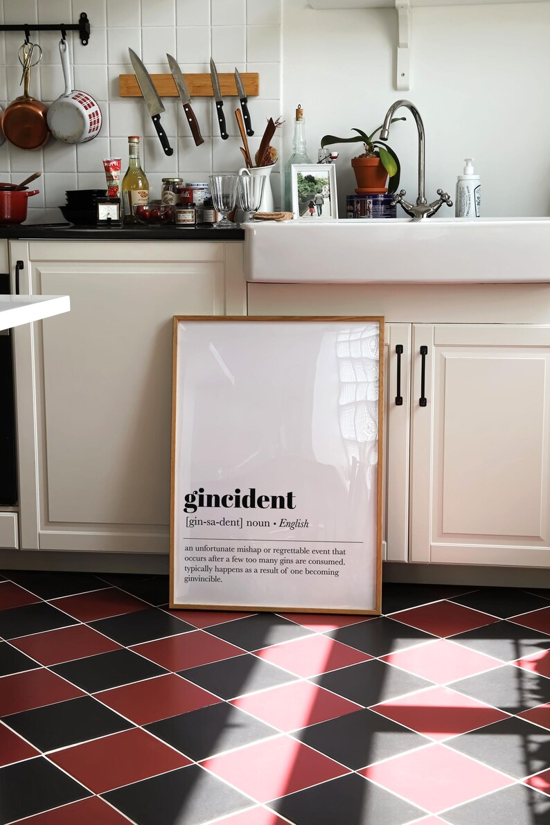 Peut inclure: Un cadre avec le mot "gincident" dans une cuisine. La d&eacute;finition de "gincident" est en dessous du mot. La cuisine a des armoires blanches, un &eacute;vier et un sol &agrave; carreaux rouges et noirs.