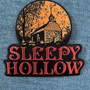 May include: A black and red embroidered patch with the words "Sleepy Hollow" and a black and white image of a church in a moonlit landscape.