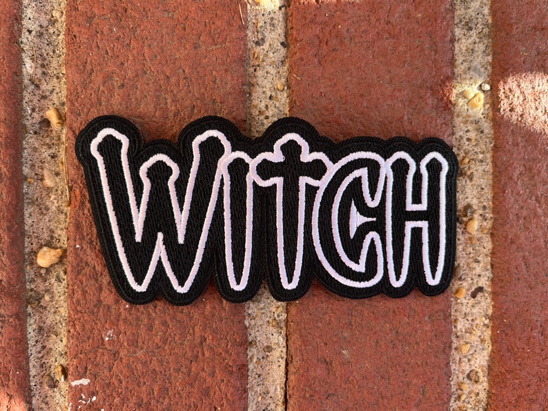 Peut inclure: Patch en tissu noir avec inscription brod&eacute;e en blanc "WITCH".