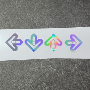 May include: Four iridescent stickers with arrow designs. The arrows point in different directions: left, down, up, and right.