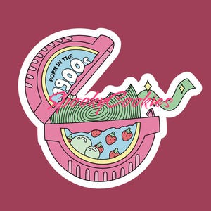 Puede incluir: Una pegatina rosa con una imagen de dibujos animados de un envoltorio de chicle con el texto "Born in the 900s" en la parte delantera. El envoltorio est&aacute; abierto y hay un chicle verde y blanco en el interior. Tambi&eacute;n hay fresas y bolas verdes dentro del envoltorio.