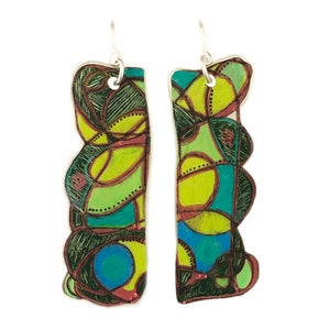 May include: A pair of abstract art earrings with green, blue, yellow, and black colors. The earrings are made of metal and have a unique, geometric design.