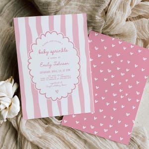 May include: Pink and white baby sprinkle invitation with vertical stripes and scalloped border. The invitation includes event details and is paired with a pink card covered in white hearts. The text reads "baby sprinkle" and "Emily Johnson".