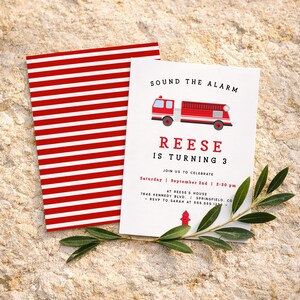 May include: A white invitation card featuring a red fire engine illustration and the words "SOUND THE ALARM". The card announces "REESE IS TURNING 3" with event details. A red and white striped card is behind it.
