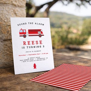 May include: A white invitation card featuring a red fire engine illustration and the words "SOUND THE ALARM". The text announces "REESE IS TURNING 3" with event details. A red and white striped card is also visible.