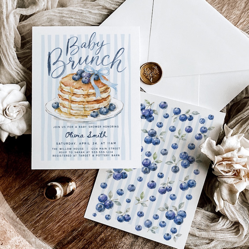 May include: A rectangular baby shower invitation card featuring a watercolor illustration of a stack of pancakes with blueberries and a blue ribbon, with the text Baby Brunch, Olivia Smith, and event details, alongside a matching blueberry patterned card.