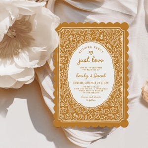 May include: A mustard-coloured wedding invitation with a scalloped edge and floral design. The invitation includes the text "Nothing Fancy, Just Love" and details for Emily & Jacob's wedding, including the date, time, and location.