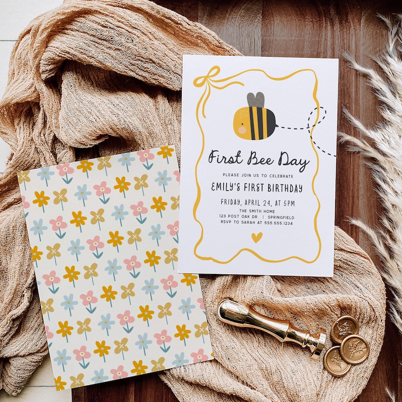 May include: Two cards with a bee theme. One card has a floral pattern in yellow, pink, and blue. The other card says "First Bee Day" with a bee graphic. A gold wax seal and stamp are also present.