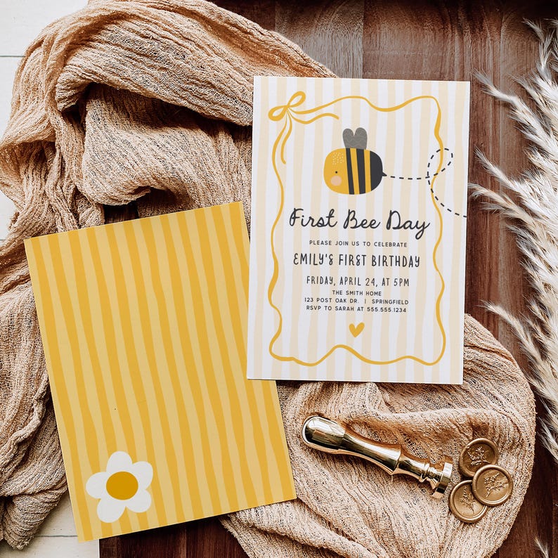 May include: Two-sided invitation with a bee theme. The front features a cartoon bee and the text "First Bee Day" with event details. The back has yellow stripes and a white daisy. A gold wax seal and a beige cloth are in the background.