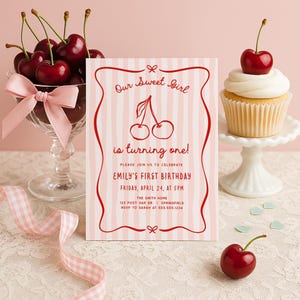 Peut inclure: Une invitation d'anniversaire sur le thème des cerises. L'invitation a un fond à rayures roses et blanches avec du texte rouge qui dit "Our Sweet Girl is turning one!" et les détails du premier anniversaire d'Emily. Un cupcake avec une cerise sur le dessus et un bol de cerises sont également dans l'image.