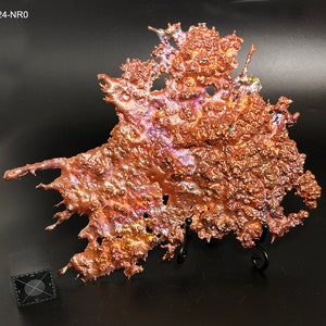 May include: A large, abstract piece of art made from copper. The copper has been melted and then cooled, creating a unique and organic shape. The piece is a deep reddish-brown color with iridescent highlights.